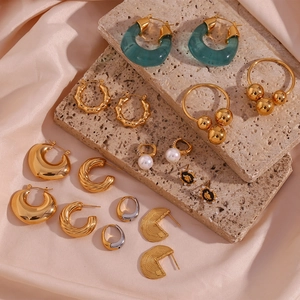 Flat lay of vintage U-shaped earrings and rings on silk and natural stone podium