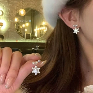 Elegant snowflake pearl earrings with zircon stones shown in a warm winter model setting