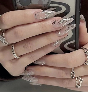 Close-up of long almond stiletto nails with silver 3D line art and Y2K metallic decor