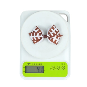 Detail showing a football print ribbon bow on a scale weighing approximately 4.1 grams