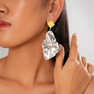 Macro detail of geometric square gold stud and irregular silver crumpled metal earring