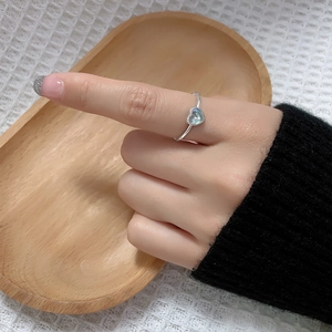 Close-up of heart-shaped moonstone ring with blue glow on minimalist silver band