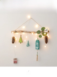 Detail of wooden Christmas wall hanging with LED lights, pine cones and Merry Christmas sign