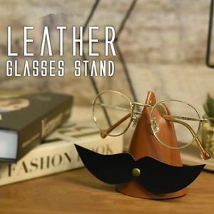 Detailed view of a creative brown leather glasses stand with a mustache design on a desk