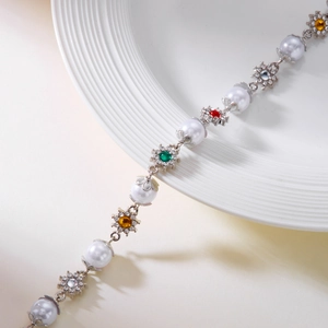 Detail of silver chain bracelet with white pearls and colorful gemstone flower charms