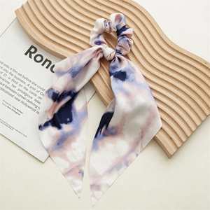 Detail of pink and blue tie-dye silk scrunchie with long ribbon on a wooden stand