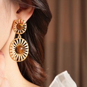 Close-up of vintage gold hollow-out drop earrings with tiger eye stone on model