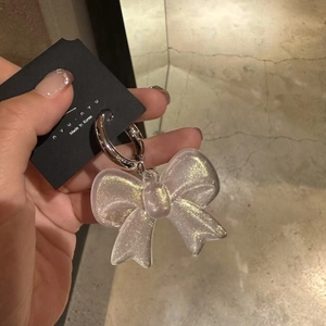 Detail of transparent acrylic bow charm with gold glitter and silver metal keyring