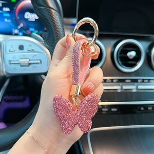 Pink crystal butterfly keychain with rhinestones shown in luxury car interior