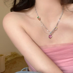 Close-up of a beaded necklace with pink heart crystal and colorful pearls on a female model