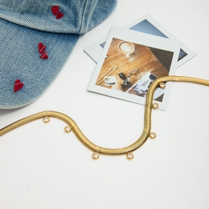 Flat lay of a gold snake chain necklace with round zircon charms on a white background