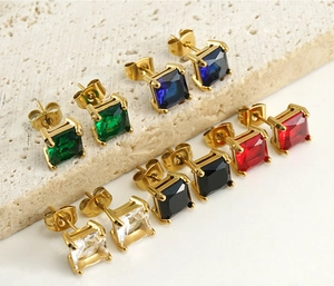 Detail of square-cut zircon earrings in five colors on a textured stone surface