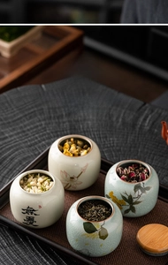 Detailed view of ceramic tea canisters with lotus patterns and wooden lids on a tray