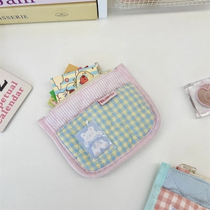 Detail of a quilted heart pattern wallet with a clear PVC card slot and bear design