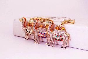 Close-up of four crystal camel keychains with enamel and gold plating on a white box