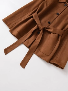 Detail eines braunen Cardigans aus Wildlederimitat mit schwarzen Knöpfen und Taillengürtel