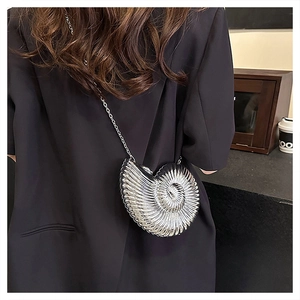 Close-up of the silver nautilus-shaped crossbody bag with radial texture and chain strap