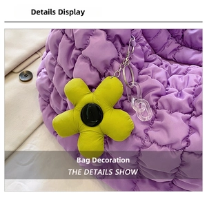 Detail of purple quilted puff tote bag with vibrant yellow flower charm and acrylic chain