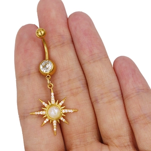 Detail eines goldenen Bauchnabelpiercings mit Sternanhänger und weißem Opalstein in der Hand