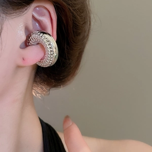 Gros plan sur la manchette d'oreille torsadée argentée avec motif martelé sur l'oreille