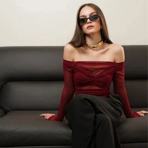 Detail of burgundy mesh off-the-shoulder top featuring ruched texture and long sleeves
