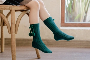 Toddler knee-high ribbed socks in dark green with cute pom-pom bow on a child model