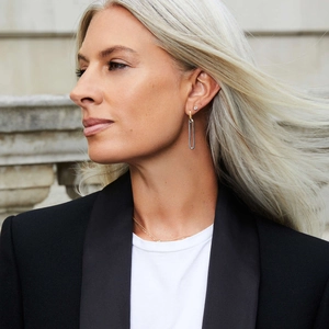 Detail of two-tone 18K gold and silver dangling paperclip earrings on a model