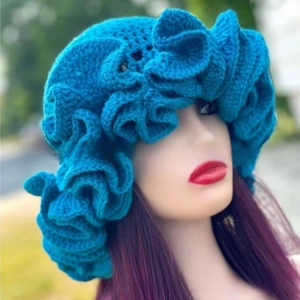 Detail of dark blue handmade crochet knit hat featuring layered ruffle brim and floral design