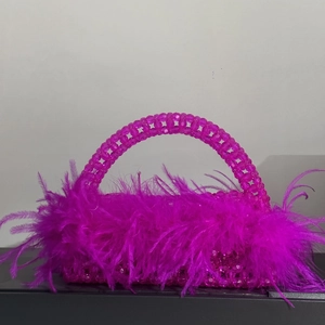 Close-up of fuchsia beaded evening bag featuring luxurious ostrich feather accents