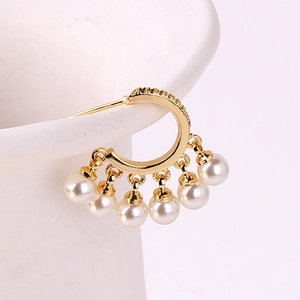 Detail of gold hoop earrings with sparkling small diamonds and white pearl tassels