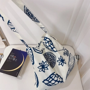 Détail d'un sac fourre-tout en toile crème avec des imprimés floraux et de fruits bleu marine
