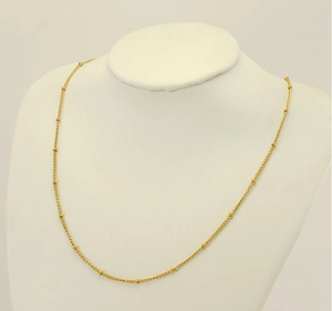 Detail of 18K gold vacuum plated beaded chain necklace on white jewelry display