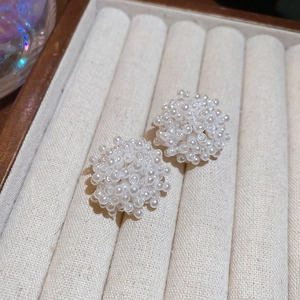 Gros plan de boucles d'oreilles élégantes en grappes de perles blanches sur velours