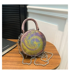 Detail of unique clock face pattern on round crossbody bag with shimmering purple-gold finish