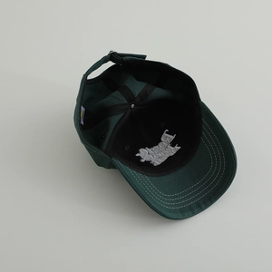 Détail de la casquette vert foncé avec broderie interne et boucle métallique argentée