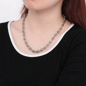 Détail d'un collier à gros maillons en acier titane argenté porté par une femme