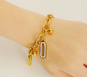 Détail d'un bracelet en acier inoxydable doré 18K avec breloques ovales et pavé diamants