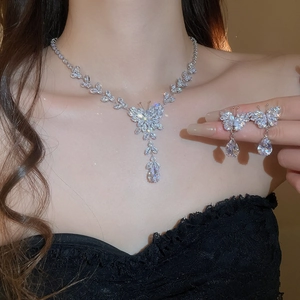 Close-up of zircon butterfly tassel necklace and matching drop earrings on a model