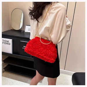 Detailed view of red floral evening bag with 3D roses and golden metal handle
