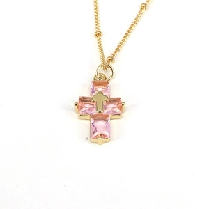 Detailed view of pink crystal cross pendant with a small gold cross on a gold chain