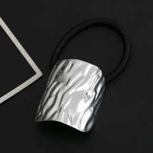 Macro detail of silver hair tie showing rippled water texture on metallic plate