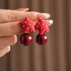 Close-up of red star fabric earrings with white polka dots and dark red pearl beads