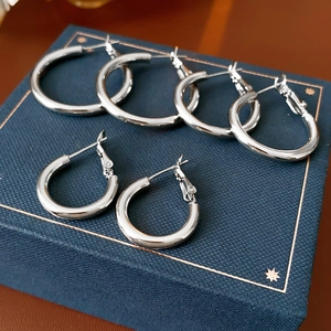 Close-up of three pairs of silver hoop earrings on a velvet blue jewelry box lid