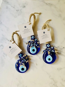 Detailed view of three glass evil eye charms with jute rope on marble background