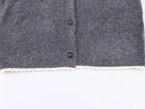 Detail of grey knitted cardigan showing lace hem trim and dark grey four-hole buttons