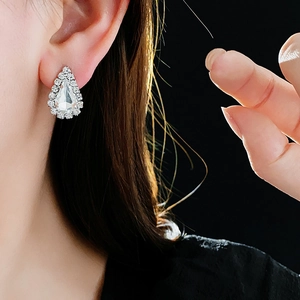 Détail de boucles d'oreilles goutte d'argent avec cristaux sur modèle, fond noir