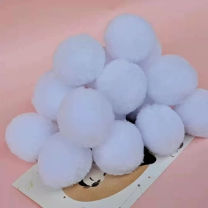 White plush pompoms for DIY crafts and Christmas costume decoration on pink background