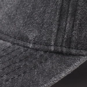Macro detail of high-quality charcoal grey wool texture and stitching on a baseball cap