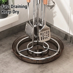 Rotating stainless steel kitchen utensil holder with a clear drip tray on marble countertop