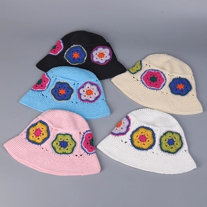 Flat lay of colorful crochet bucket hats with vibrant floral knit patterns on grey background
